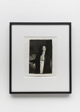 Bianca Jagger in Black Coat in Hotel Room