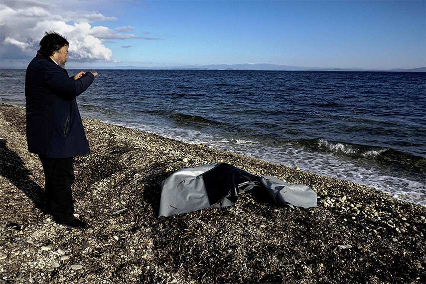 Ai Weiwei takes a picture of the remains of a rubber boat