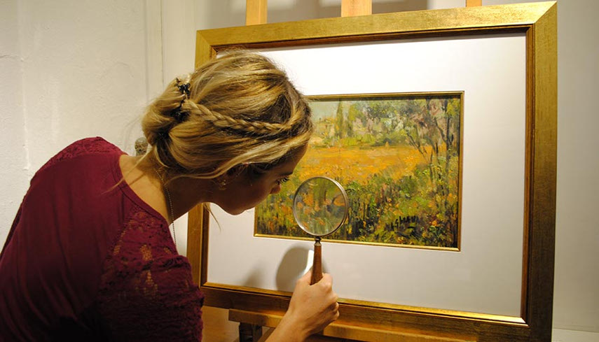 Photo of an appraiser taking a closer look at the painting, determining it's sales information and use