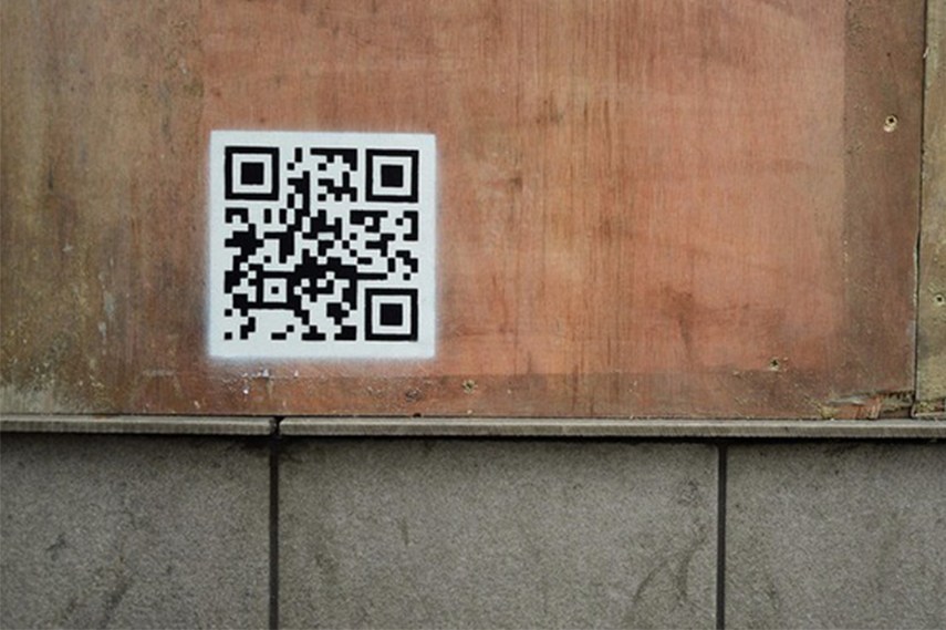 QR code as part of the Banksy's stencil, leading the viewer to a video of the police raid in the camp